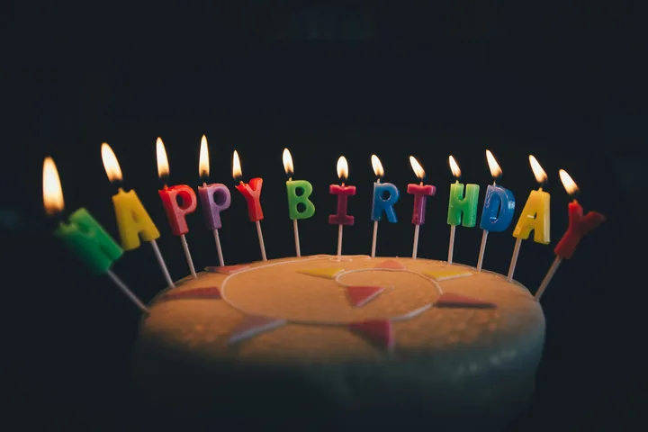 A homemade birthday cake with lit letter-shaped candles