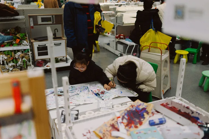 Two children bent over their drawings at a busy craft table