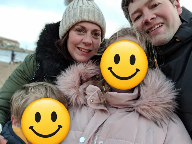 The family behind Kins smiling by the sea